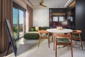 A modern living room with a sofa, a dining table, and chairs. There is a kitchen area with a refrigerator and a sink. - Diastar Luxury Suite in Heraklion Crete A3 (Xeropotamos)