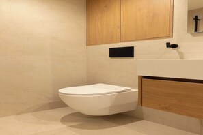A modern bathroom with a white toilet, wooden cabinets, and a black control panel. - Elegant flat - 3BR-8P- Canal Saint-Martin (Paris)