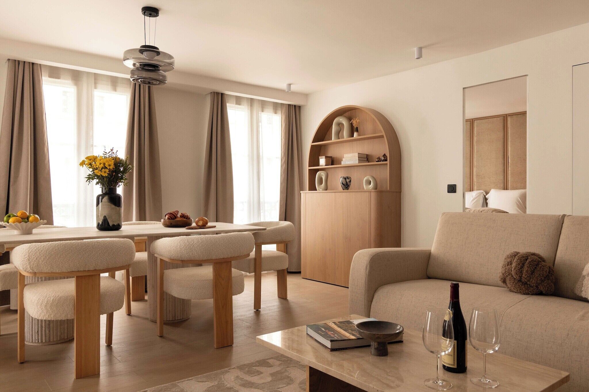 A modern living room with a sofa, dining table, chairs, and a wooden cabinet.