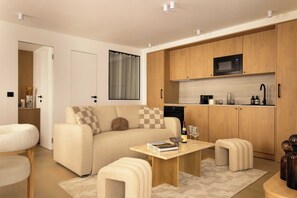 A modern living room with a sofa, a coffee table, and a kitchen area with wooden cabinets and a microwave. - Elegant flat - 3BR-8P- Canal Saint-Martin (Paris)