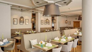 A restaurant with booths and tables, each set with plates, glasses, and candles.