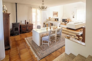 A spacious living area with a dining table, chairs, a fireplace, and a chandelier.
