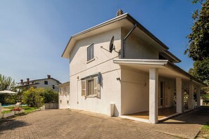 A two-story house with a covered porch and a satellite dish.