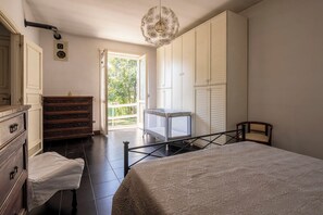 A bedroom with a bed, a dresser, a chair, a window, and a door.