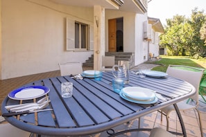 An outdoor dining area with a table set for four, surrounded by chairs.