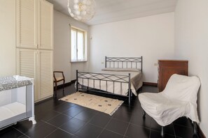 A bedroom with a bed, a chair, a wardrobe, and a window.
