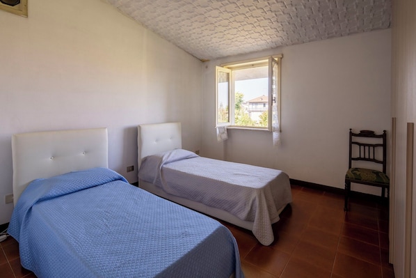 A room with two beds, a window, and a chair.