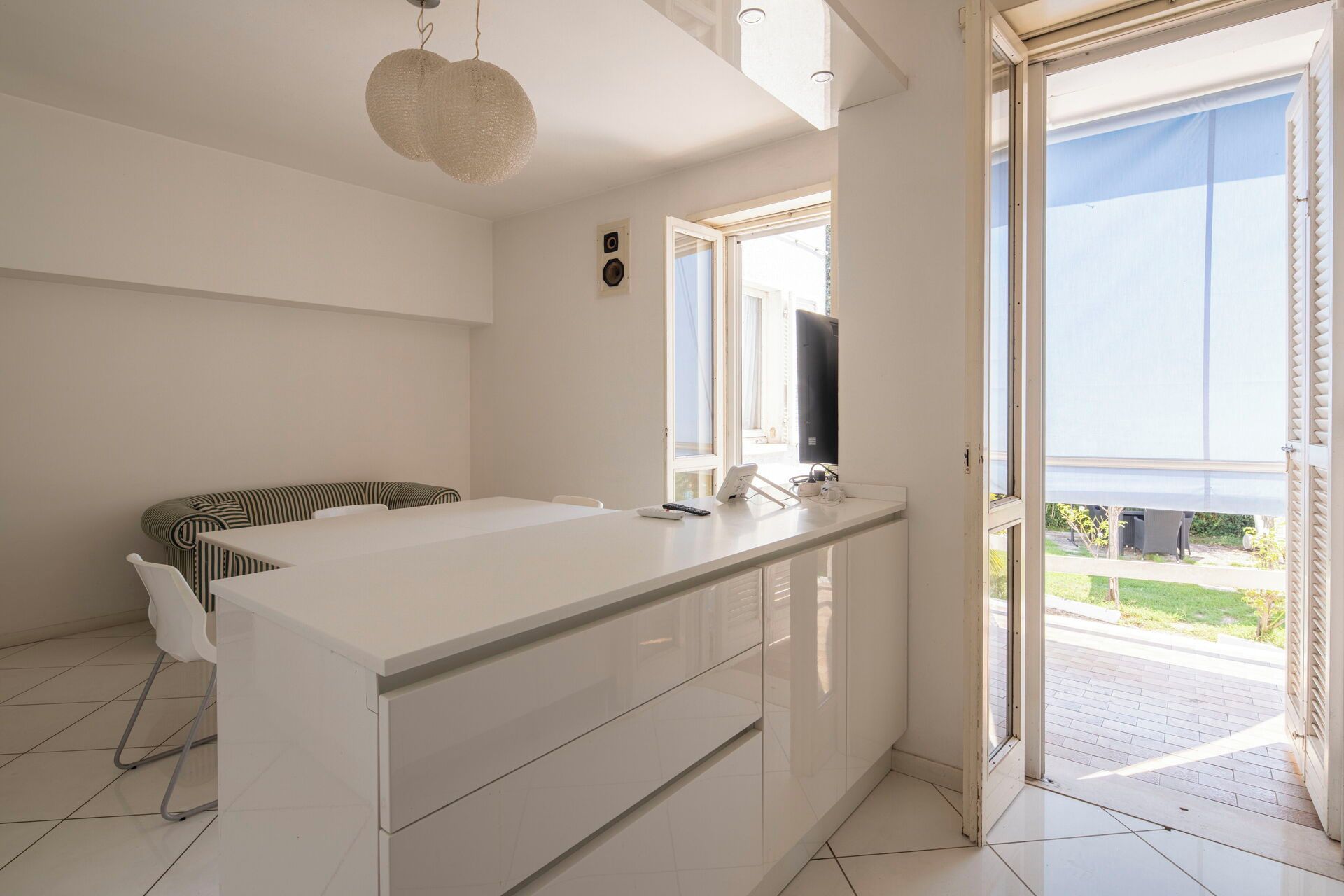 A modern bedroom with a large bed, a desk with a computer, and a view of the outdoors.