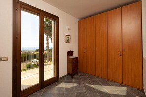A room with a sliding glass door leading to a balcony, a wooden wardrobe, and a small wooden cabinet. - Villa in Donnalucata with 2 bedrooms sleeps 6 (Donnalucata)