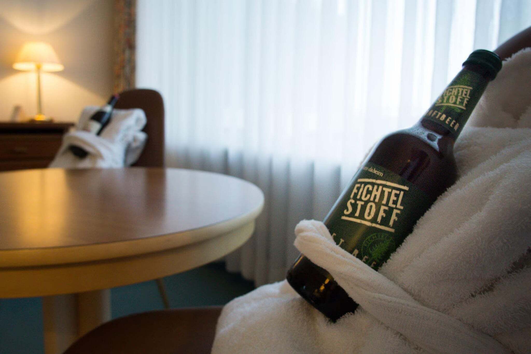 Uma garrafa de cerveja Fichtel Stoff sendo segurada por alguém de roupão.