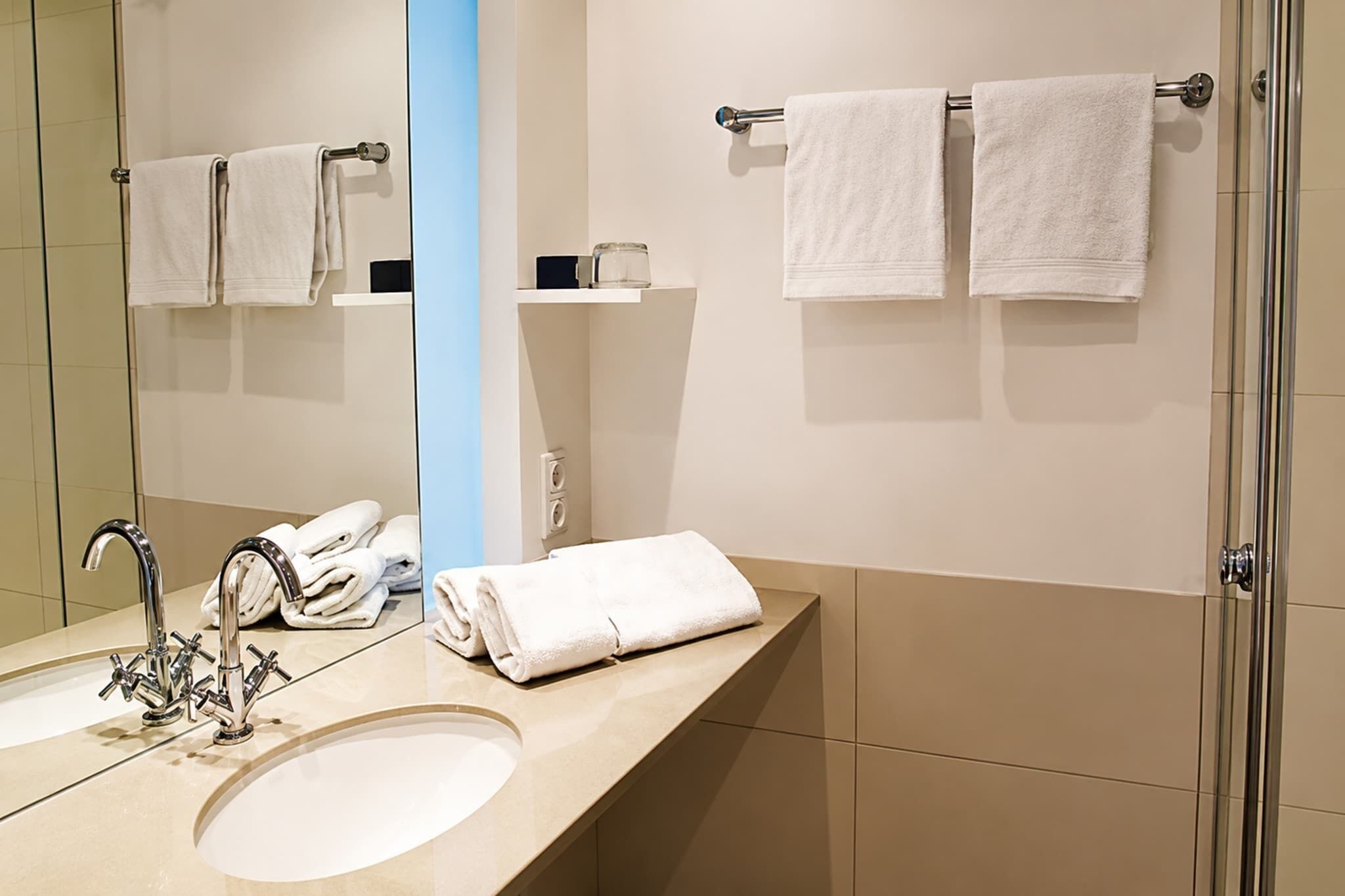 A modern bathroom with a sink, mirror, and two towel racks.