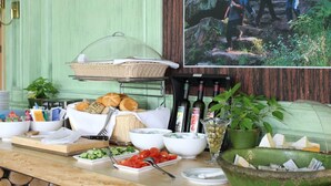 A buffet setup with various food items, a wine bottle holder, and a framed picture on the wall.