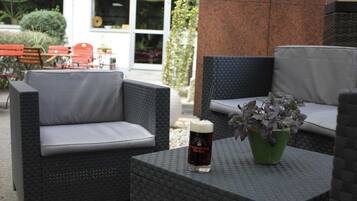 Outdoor wicker furniture with cushions, a glass of beer, and a potted plant.