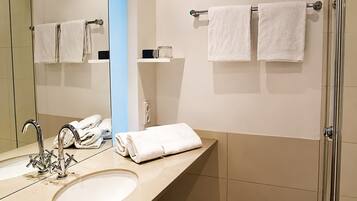 A modern bathroom with a sink, mirror, and two towel racks.