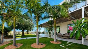 Ein moderner Außenbereich mit Palmen, einem Pool und Gartenmöbeln.