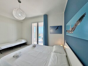 A hotel room with a large bed, a smaller bed, a hanging light fixture, a window with curtains, and a wall-mounted painting of a bird. - Villa in Marina Di Ragusa with 3 bedrooms sleeps 7 (Marina Di Ragusa)