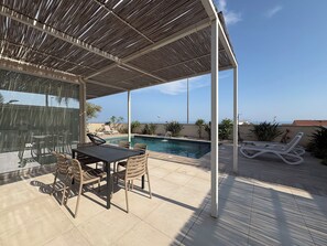 A covered outdoor area with a pool, lounge chairs, and a table with chairs. - Villa in Marina Di Ragusa with 3 bedrooms sleeps 7 (Marina Di Ragusa)