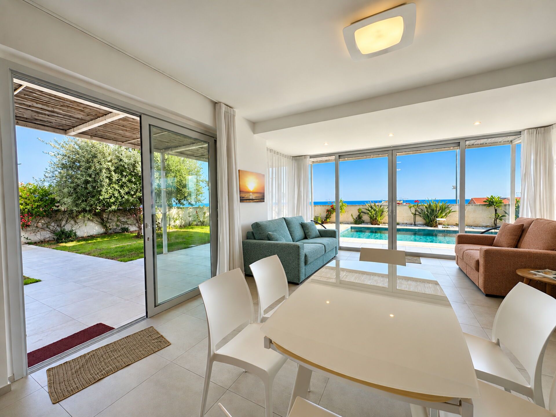 A modern living room with a pool view, a dining area, and a sofa.