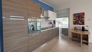 Eine moderne Küche mit Holzausstattung, einem Backofen und einem Fenster mit Blick auf einen Balkon.