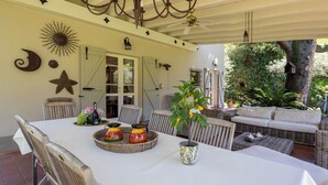 An outdoor dining area with a table, chairs, a wicker sofa, and a ceiling fan. - Villa El Perlè by Geco Vacation Rentals (Padenghe Sul Garda)