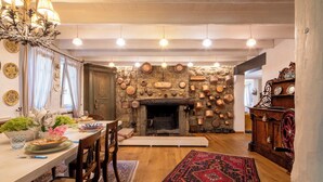 A dining area with a stone fireplace, wooden furniture, and hanging lights. - Villa El Perlè by Geco Vacation Rentals (Padenghe Sul Garda)