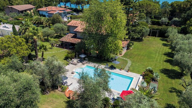 A residential property with a swimming pool, surrounded by lush greenery and a view of the sea. - Villa El Perlè by Geco Vacation Rentals (Padenghe Sul Garda)