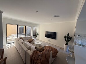 Een moderne woonkamer met een bank, televisie en cactussen.