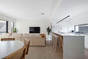 A modern living room with a sofa, a TV, and a kitchen area with a bar.