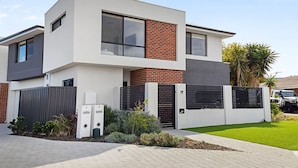 A modern two-story house with a flat roof, large windows, and a brick facade.