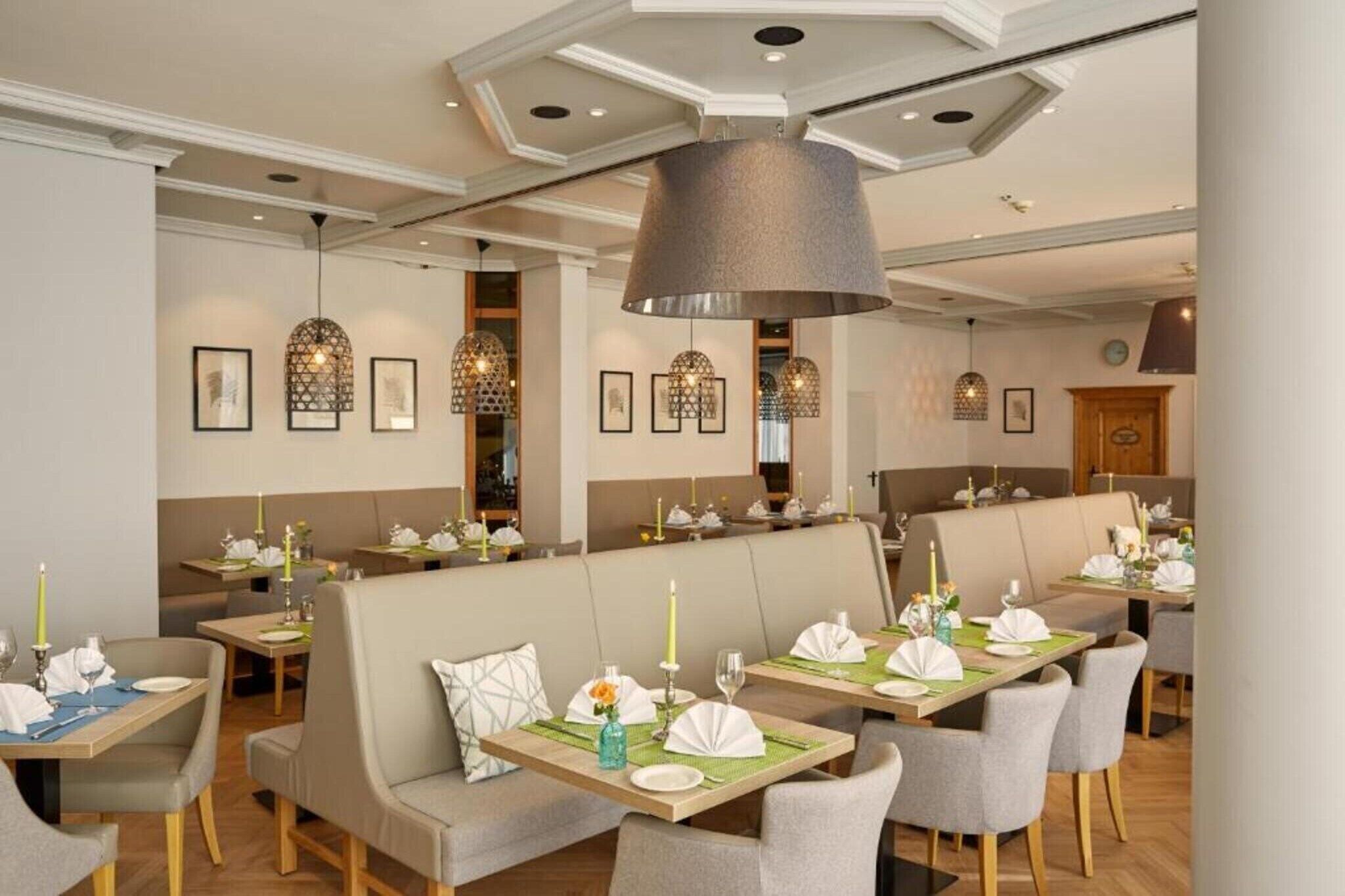 Un restaurant avec des banquettes et des tables, chacune étant dressée avec des assiettes, des couverts et des bougies.
