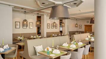 Un restaurant avec des banquettes et des tables, chacune étant dressée avec des assiettes, des couverts et des bougies.