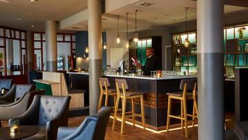En bardisk med barstolar, en bartender och en bardisk.