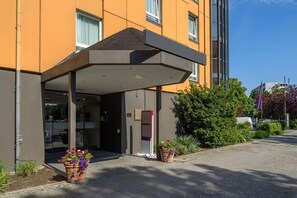 Ein Hotel mit Eingangsbereich, überdachtem Bereich, Glasüren und Topfpflanzen.