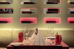 Ein Restaurantambiente mit einem für zwei Personen gedecktem Tisch, Gläsern, einer Serviette und einer Speisekarte.