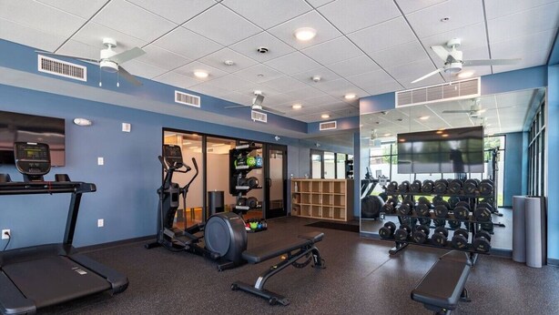 A gym with treadmills, an elliptical, free weights, and a mirror.