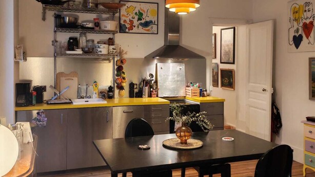 Una cocina con una mesa de comedor, sillas, una lámpara colgante y diversos utensilios de cocina.