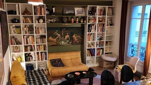 Una sala acogedora con sofá, una mesa de centro, una estantería y un comedor.
