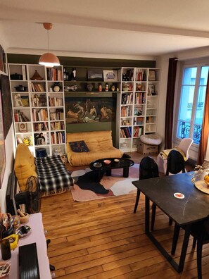 Ein gemütliches Wohnzimmer mit Sofa, Couchtisch, Bücherregal und Essbereich.
