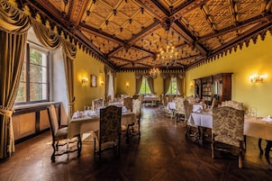 Comedor con techo de madera decorado, candelabros y muebles clásicos.