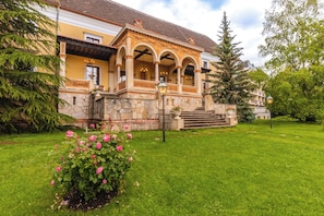 A building with a stone facade, arched windows, and a well-maintained garden with roses. - Pytloun Schlosshotel Weikersdorf (Baden)