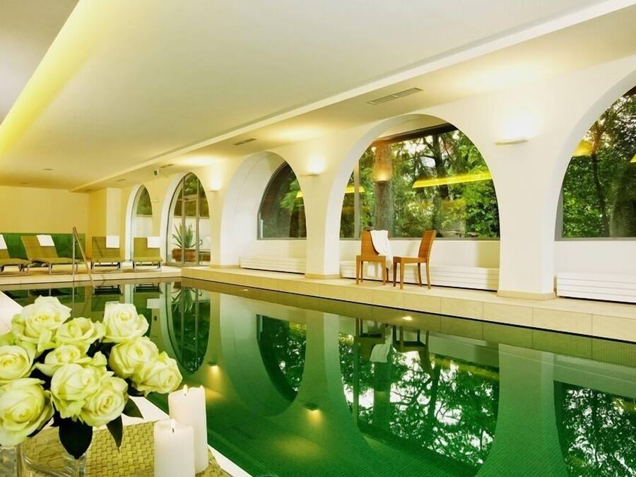 A swimming pool with lounge chairs and a vase of flowers.
