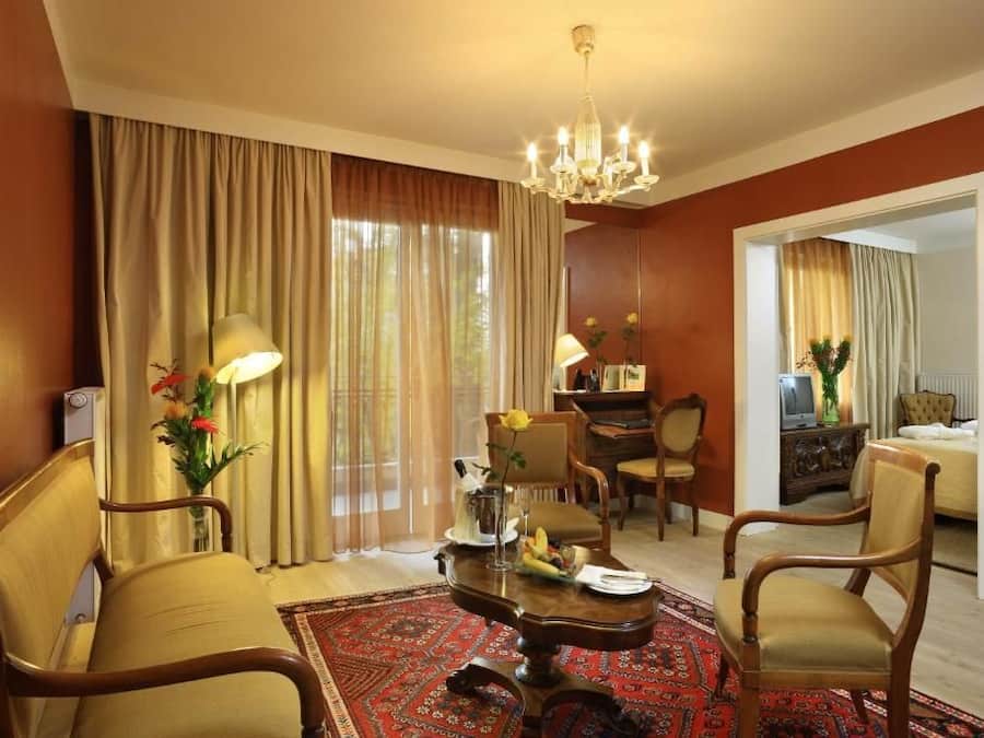 Une chambre d’hôtel avec un coin repas, un grand miroir et un lustre.
