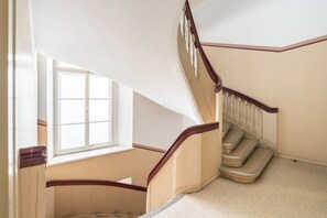 Ein Teil eines Zimmers mit einem Fenster, einer Holztreppe und einem Teppichboden.