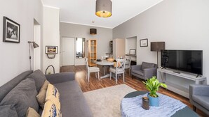 Een moderne woonkamer met een bank, een eettafel, een televisie en een plant.