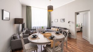 Een moderne woonkamer met een eethoek, grijze banken, een ronde tafel en een hanglamp.