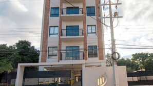 A multi-story building with a modern architectural design, featuring a central entrance with a garage, and a sign with the name 'ZUBA'. - Corporate Stays Zuba 8 -116 (Fernando de la Mora)