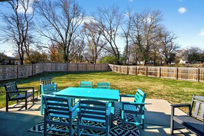 Un jardin avec une table et des chaises turquoise, une clôture en bois et une pelouse verdoyante.