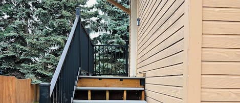 A wooden staircase leading to a building with a sloped roof and a black railing.