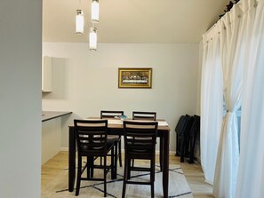 A dining area with a table, chairs, a painting, and hanging lights. - Cozy retreat offering comfort and convenience to everything! (Anchorage)