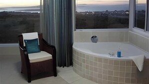 Une pièce avec une grande fenêtre, une chaise et une baignoire.
